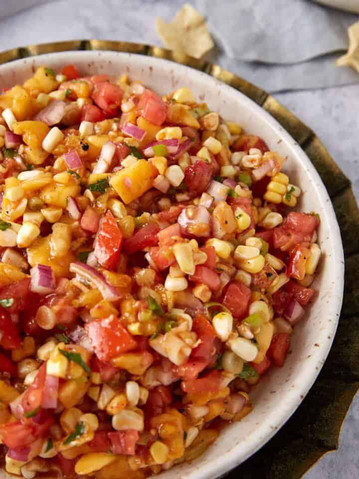 A serving bowl of fresh peach and corn salsa.
