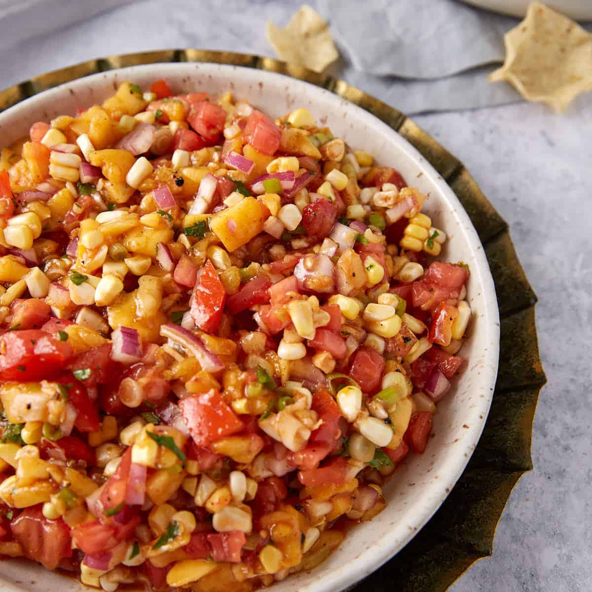 A serving bowl of fresh peach and corn salsa.