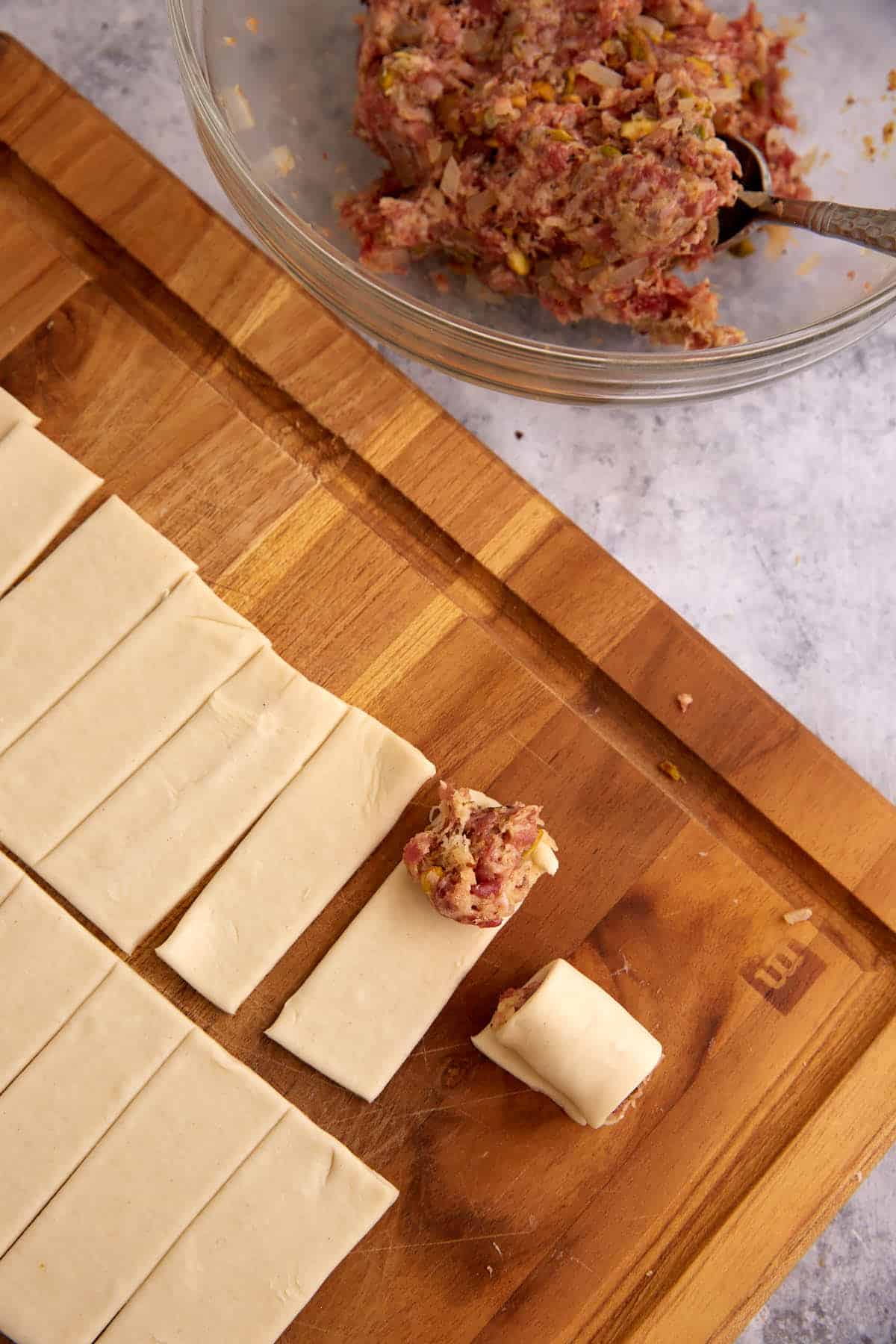 Sausage filling on the edge of a pastry strip.