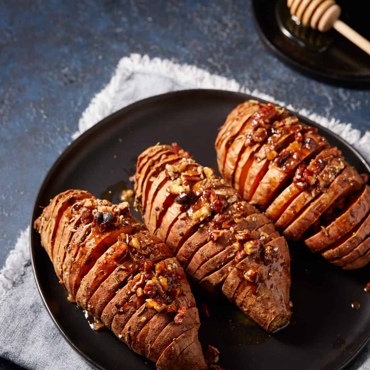 Three hasselback sweet potatoes on a platter on top of. napkin.