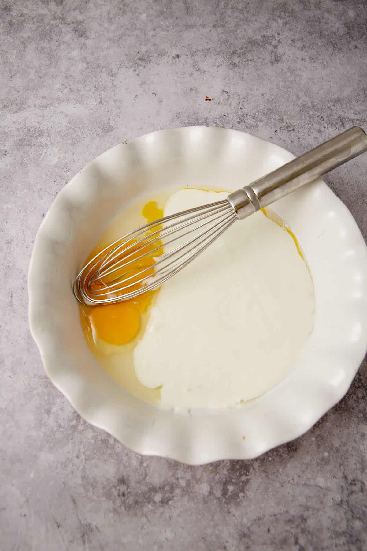Egg and buttermilk in a pie pan with a whisk.