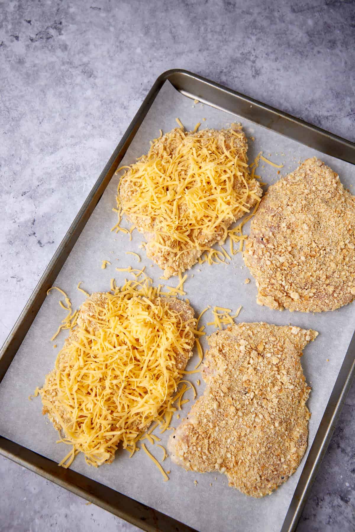 chicken on a baking sheet coated with Ritz crackers and cheese.