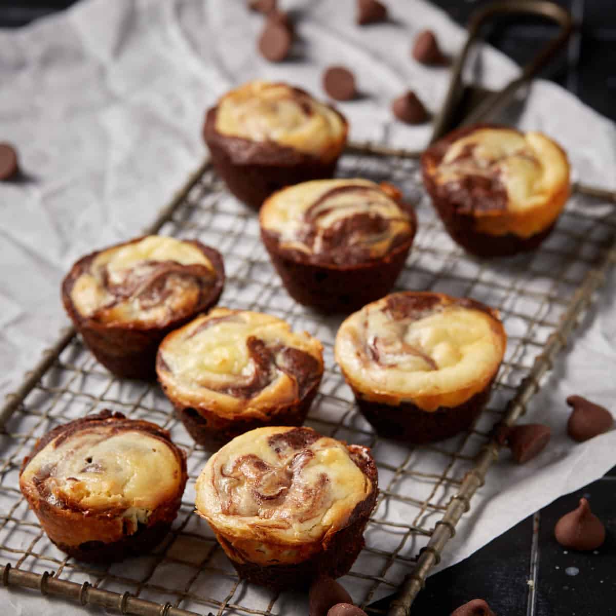 Cheesecake brownie bites on a metal wrack on parchment paper.
