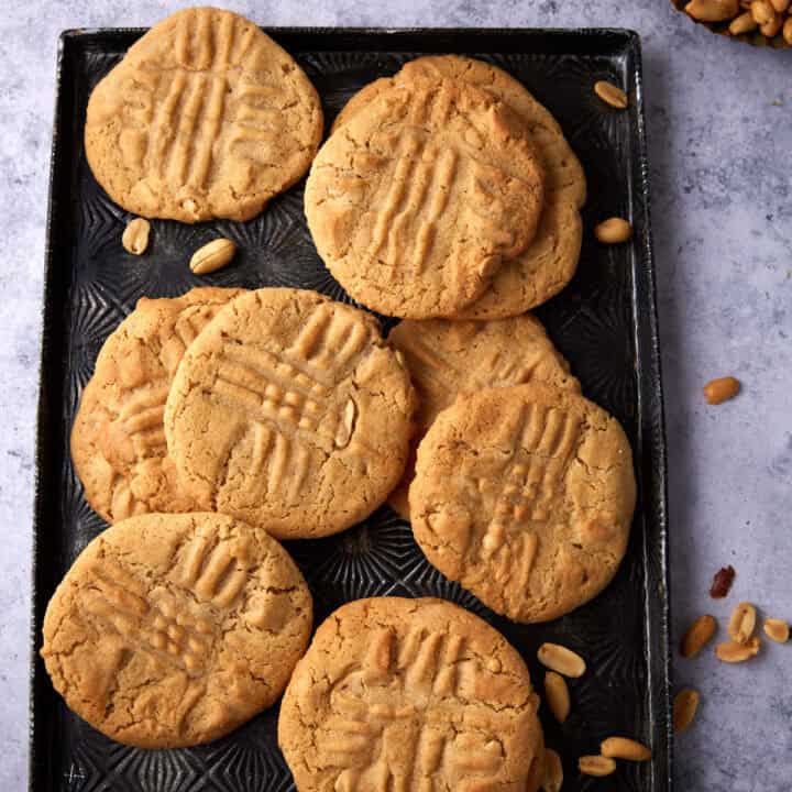 Crunchy peanut butter cookies on a black tray.