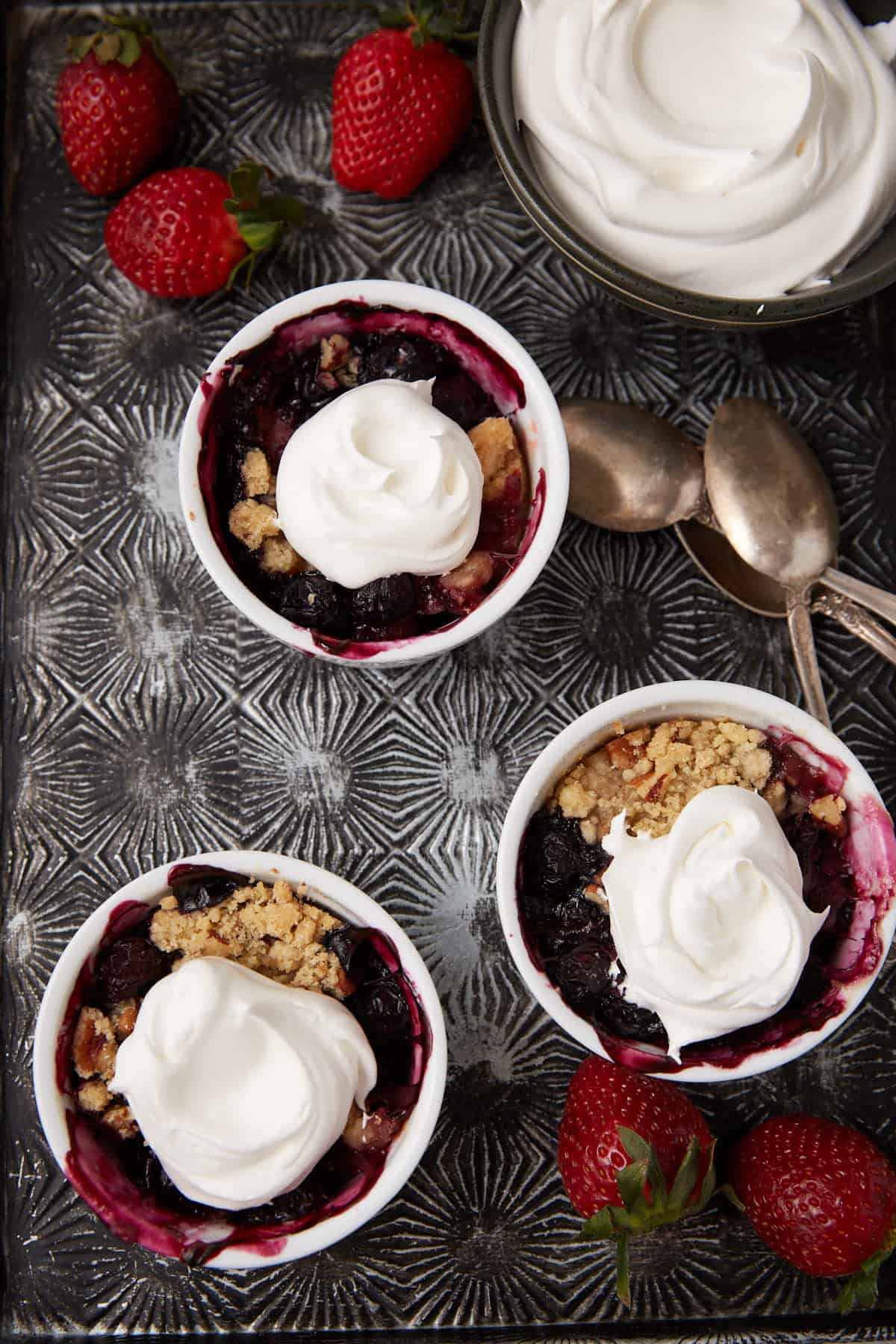 Strawberry rhubarb crisp with berries topped with whipped cream.