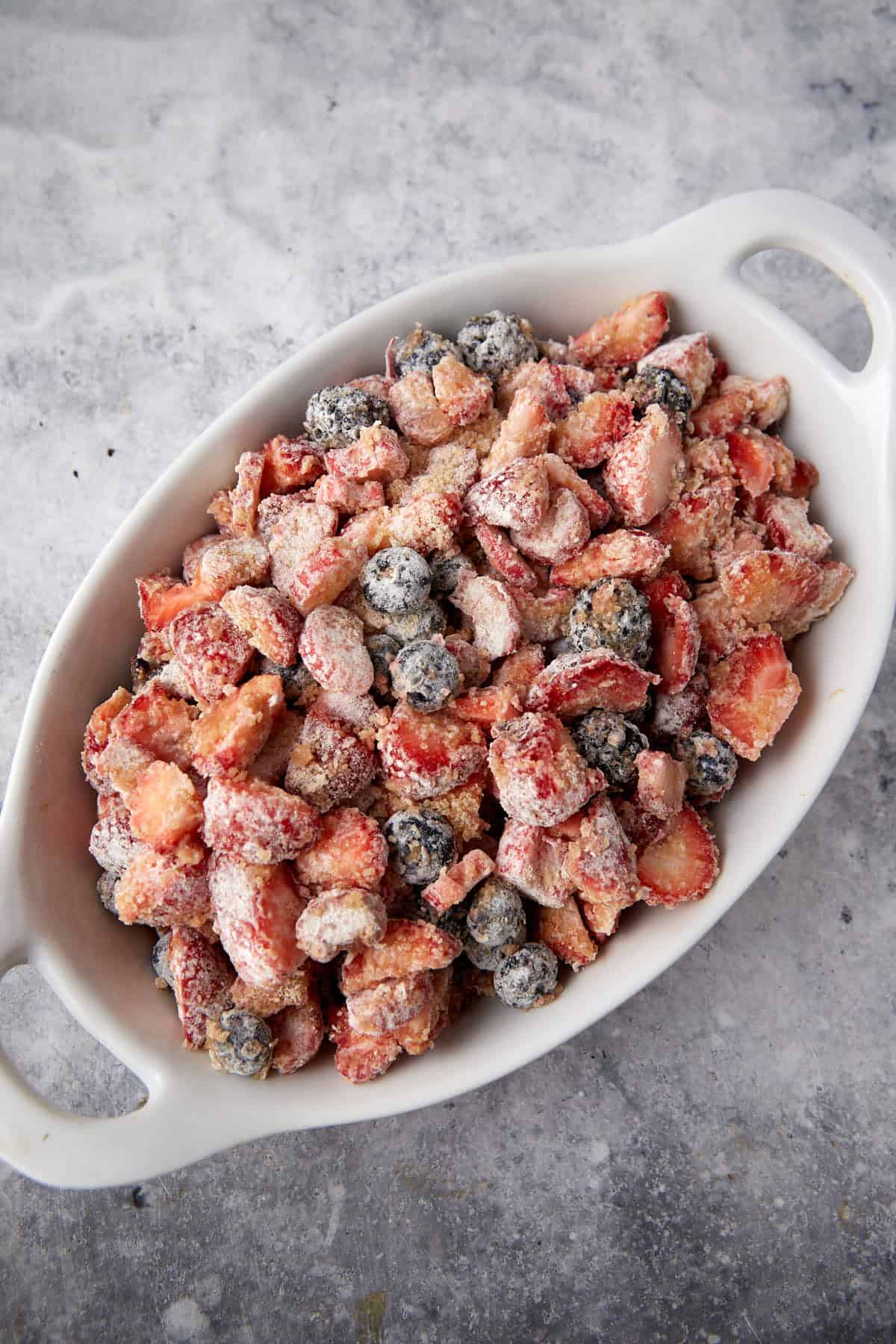 A baking dish with coated berries and rhubarb.