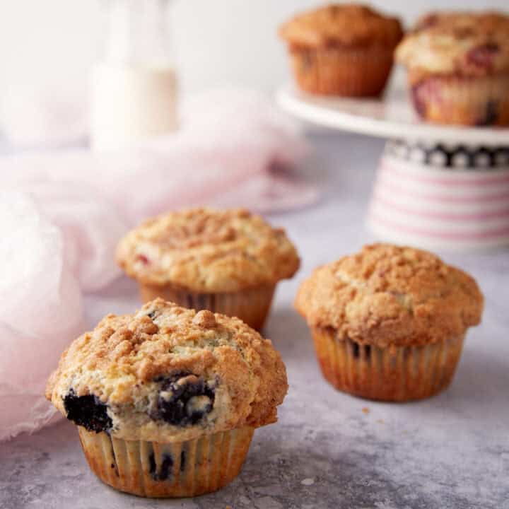 A group of muffins next to a cake stand of muffins.