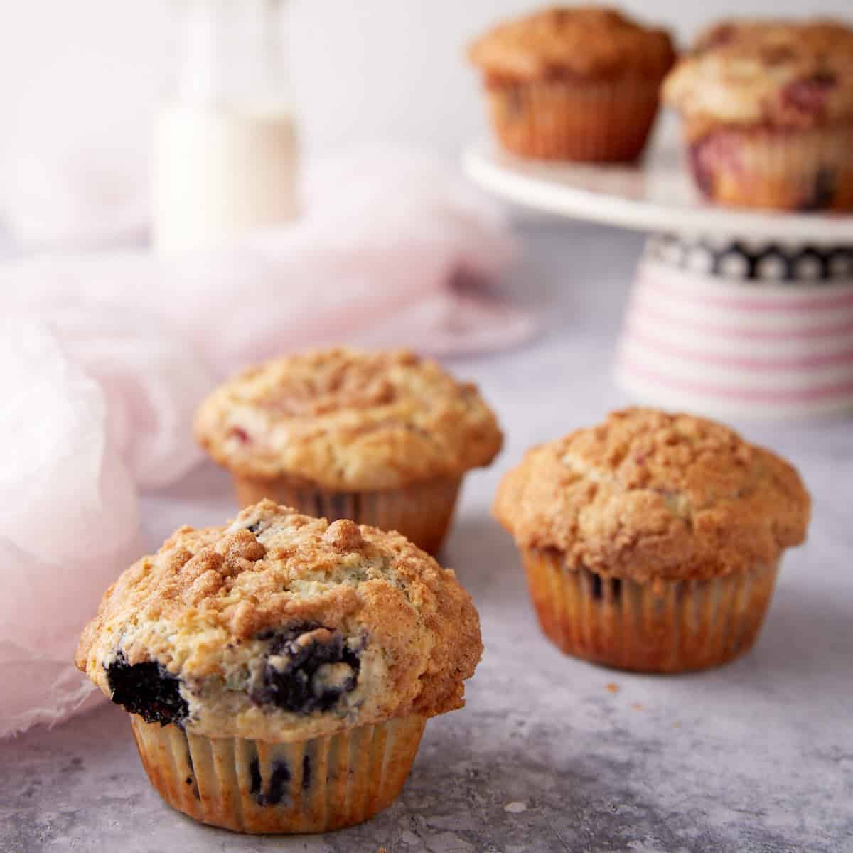 A group of muffins next to a cake stand of muffins.