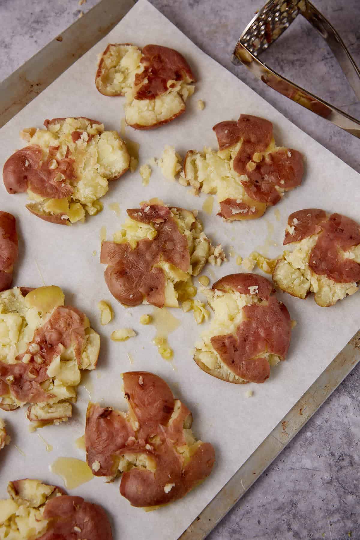 Cooked new potatoes smashed on a baking sheet.