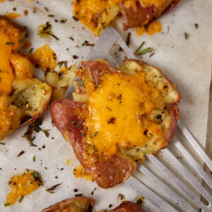 A smashed new potato being removed form a pan.