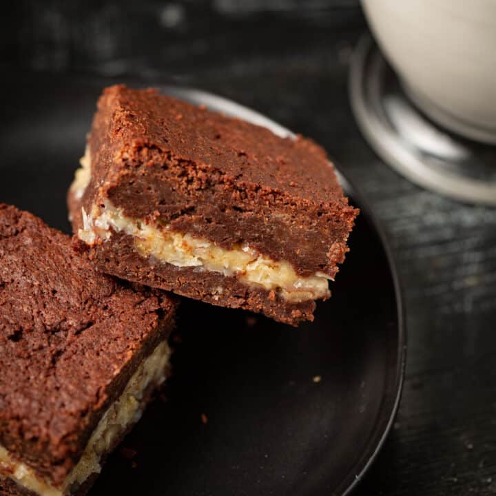 Chocolate brownies with a coconut layer on a plate.