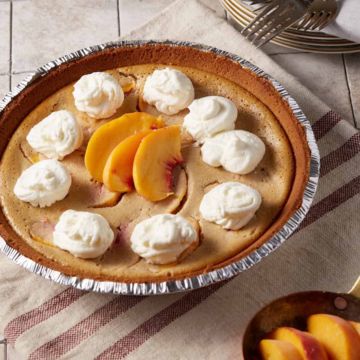 A peach pie topped with whipped cream and fresh peaches.
