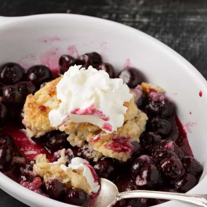 A ramekin filled with Southern blueberry cobbler with a spoon.