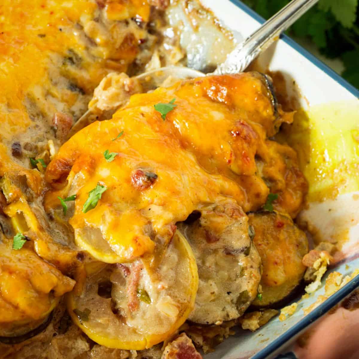 A baking dish with squash casserole covered in cheese.