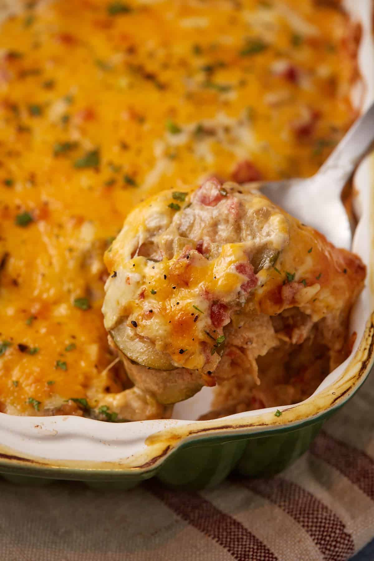 A serving spoon scooping out squash casserole.