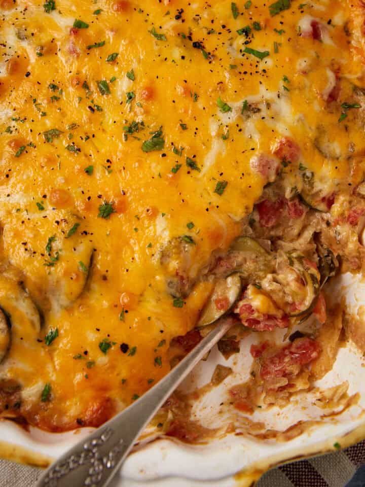 Squash casserole in a baking dish with a serving spoon.