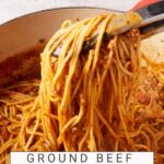 A Dutch oven with spagehtti casserole being mixed with tongs.