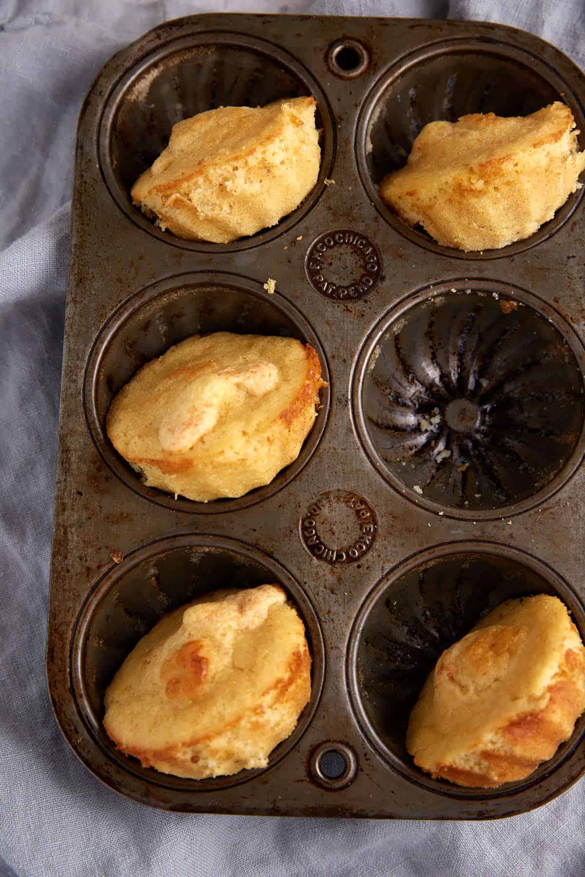 A muffin tin of baked cornmeal muffins.