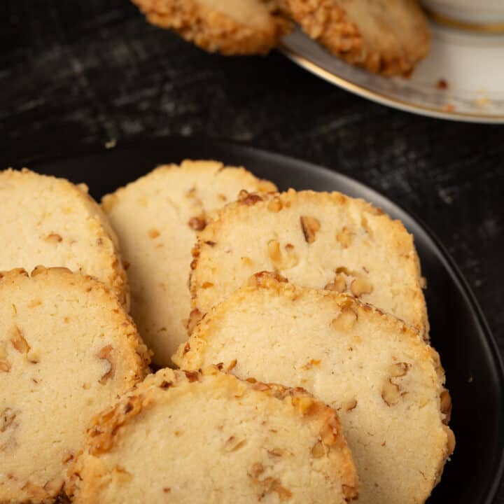 Walnut shortbread cookies on a plate next to a tea cup.