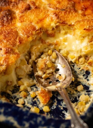 Cornbread corn pudding with a serving spoon in a casserole dish.
