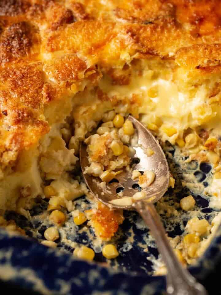 Cornbread corn pudding with a serving spoon in a casserole dish.