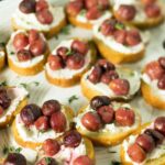 A platter of roasted grapes on bread rounds.