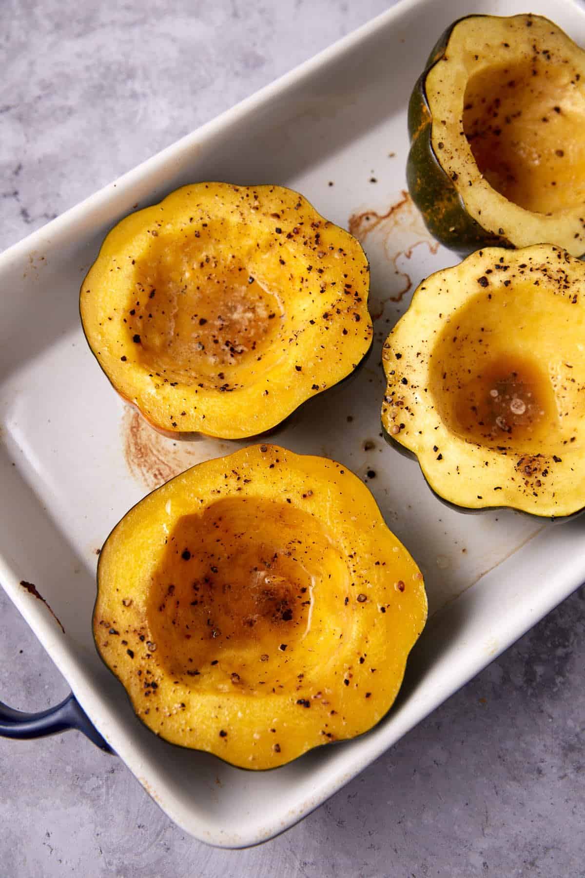acorn squash halves without stuffing in a baking dish.