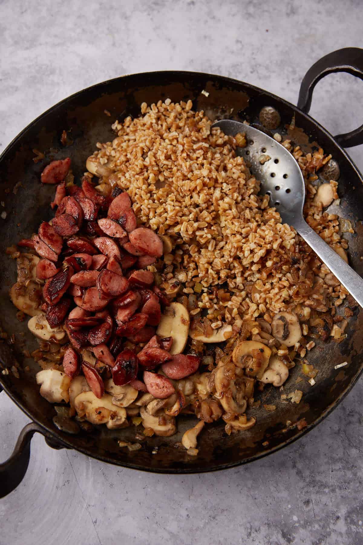 stuffed acorn squash filling in a skillet with a spoon.