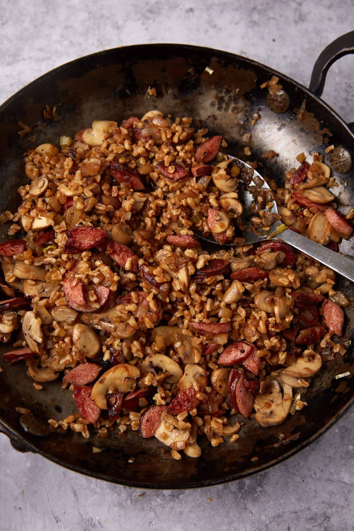 stuffed acorn squash stuffing in a skillet with a spoon.
