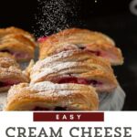 Sliced cream cheese puff pastries on a cake platter with powdered sugar.