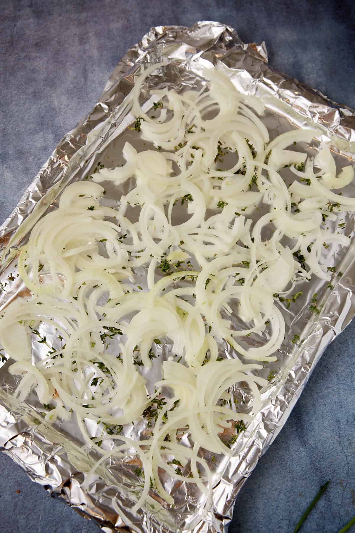 Sliced onions on a baking sheet.