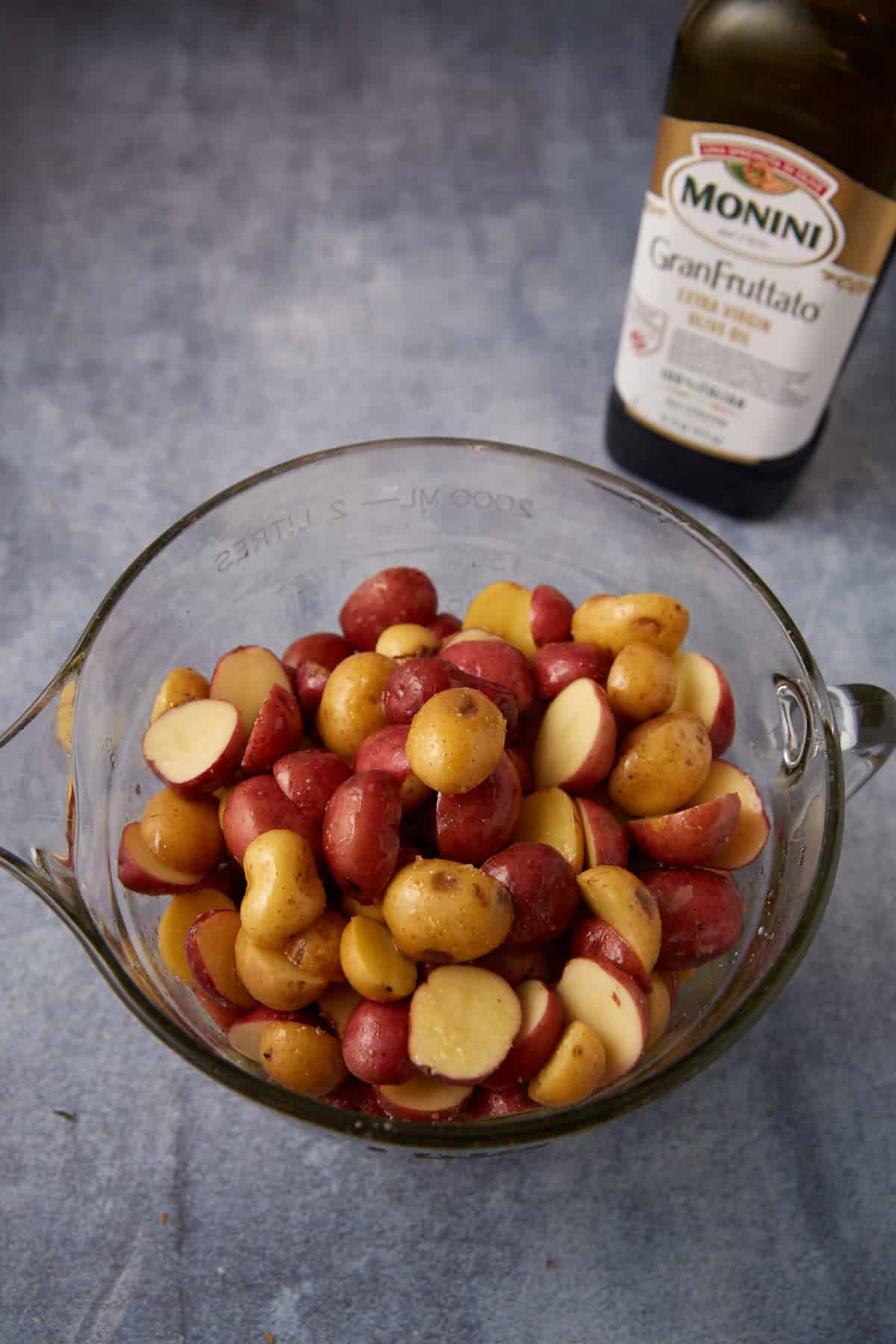 Sliced potatoes in a bowl with olive oil.