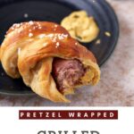A single pretzel wrapped bratwurst with a bite taken out.