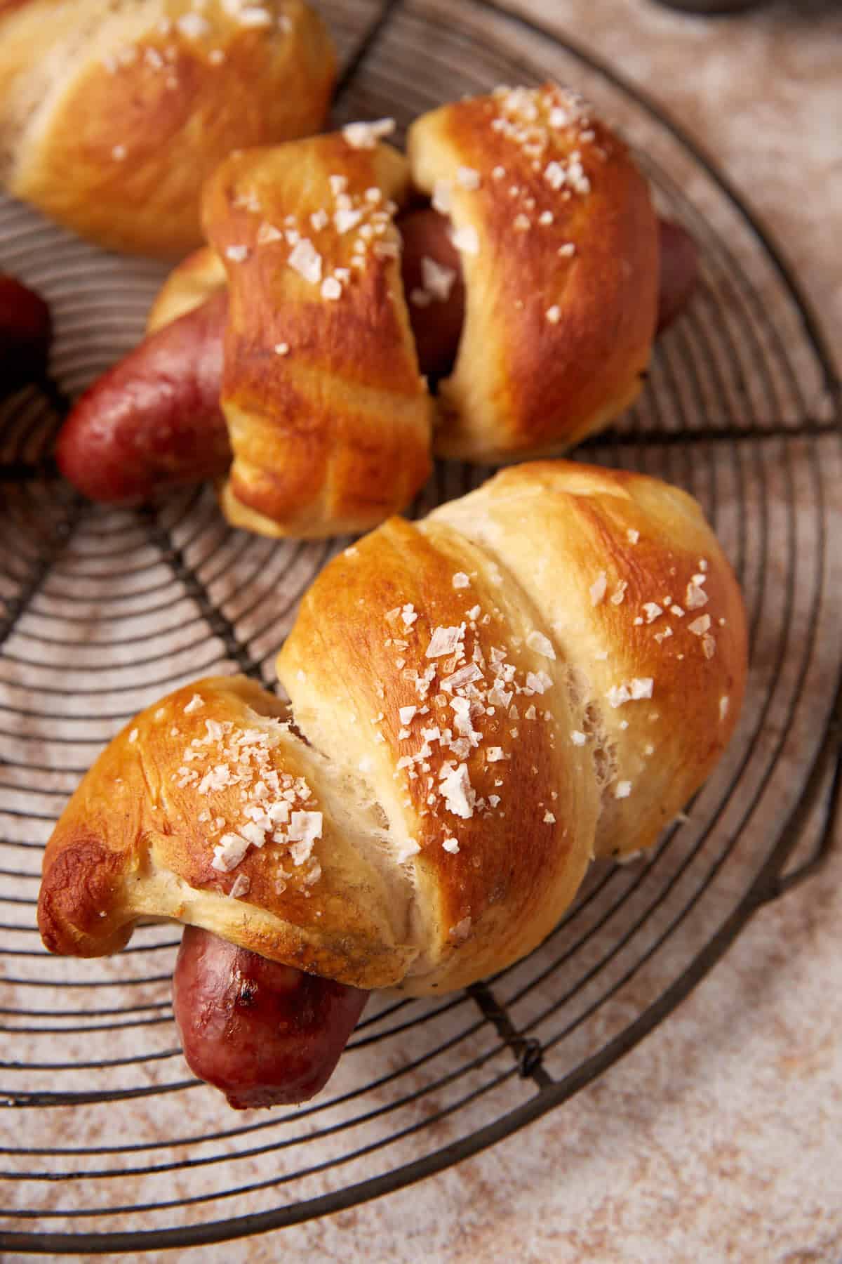 Baked pretzel bratwurst sausages on a cooling rack.