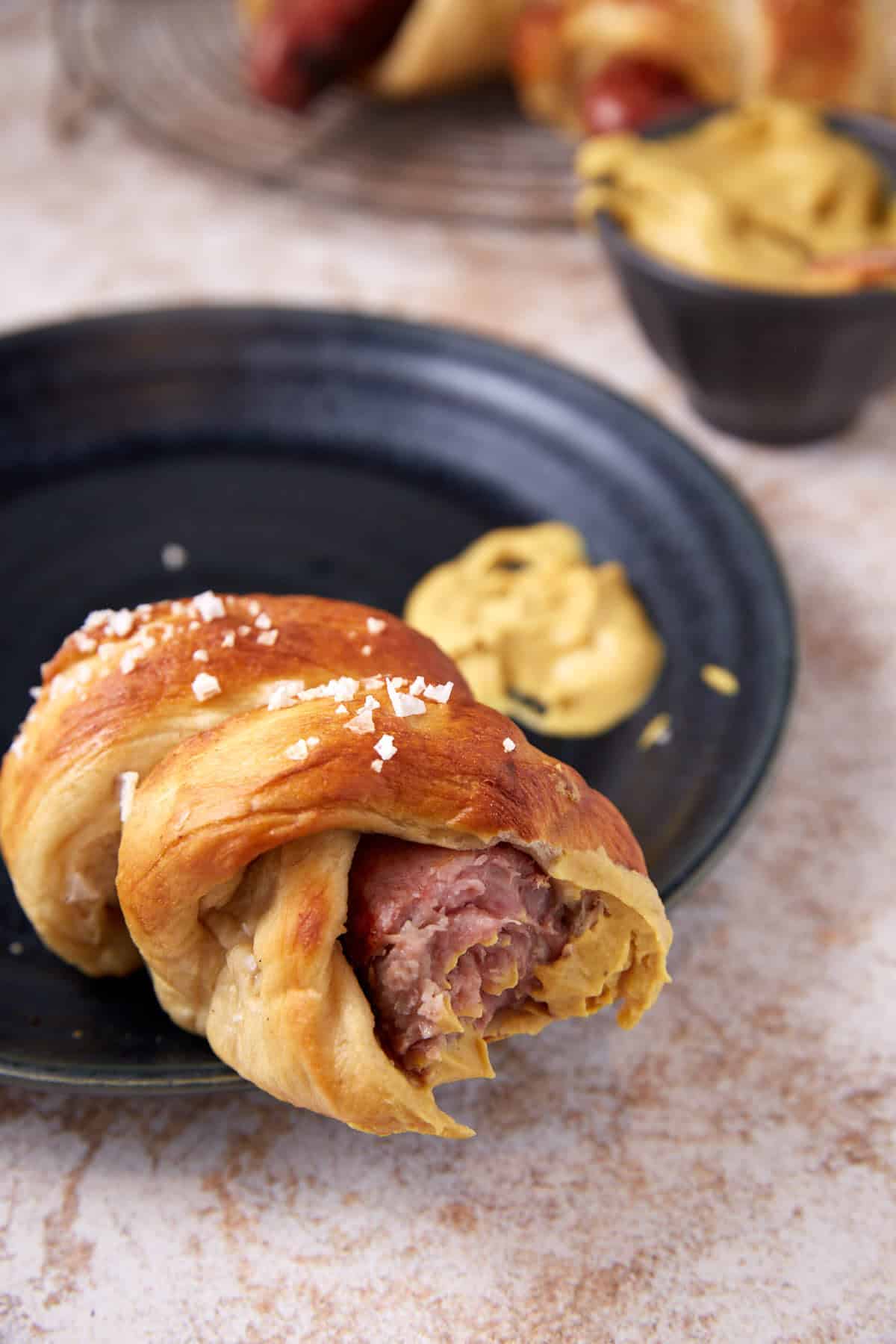 A pretzel brat with mustard on it.