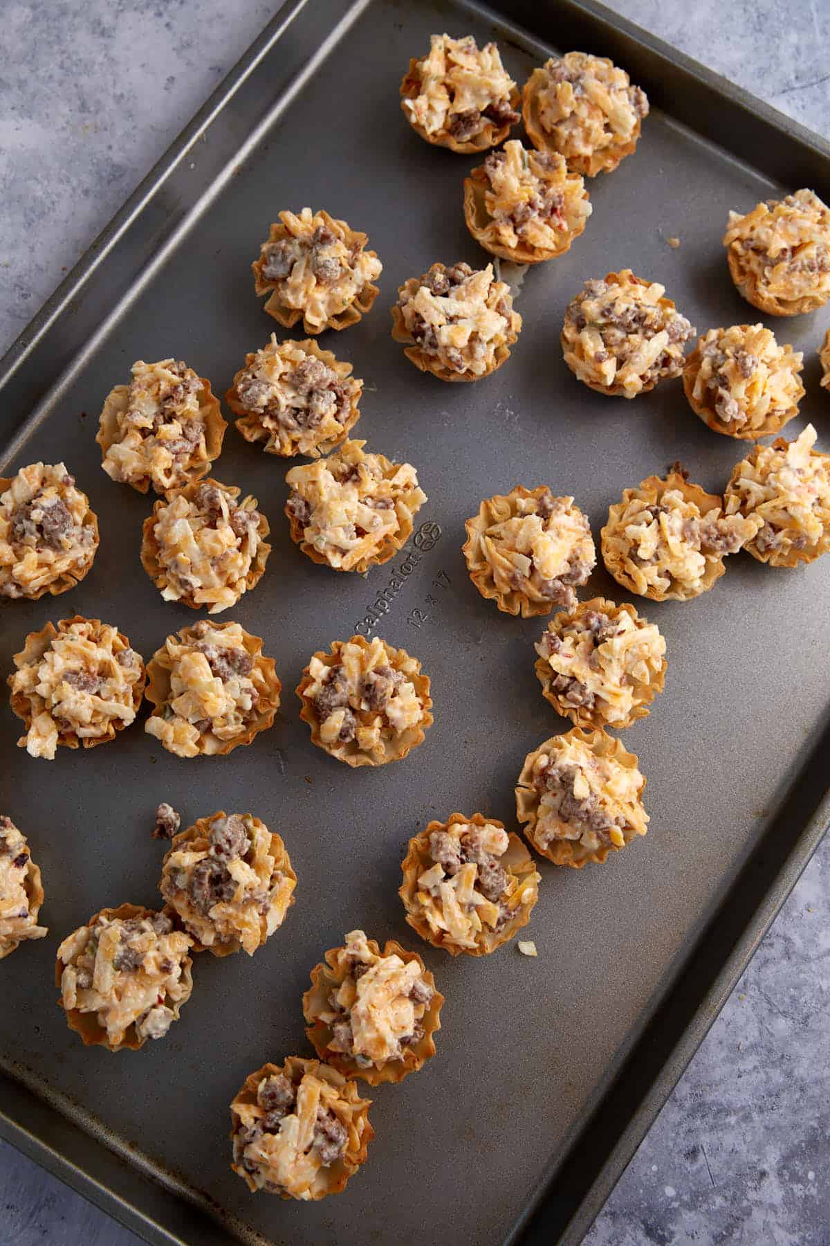 Sausage phyllo cups on a baking tray before baked.