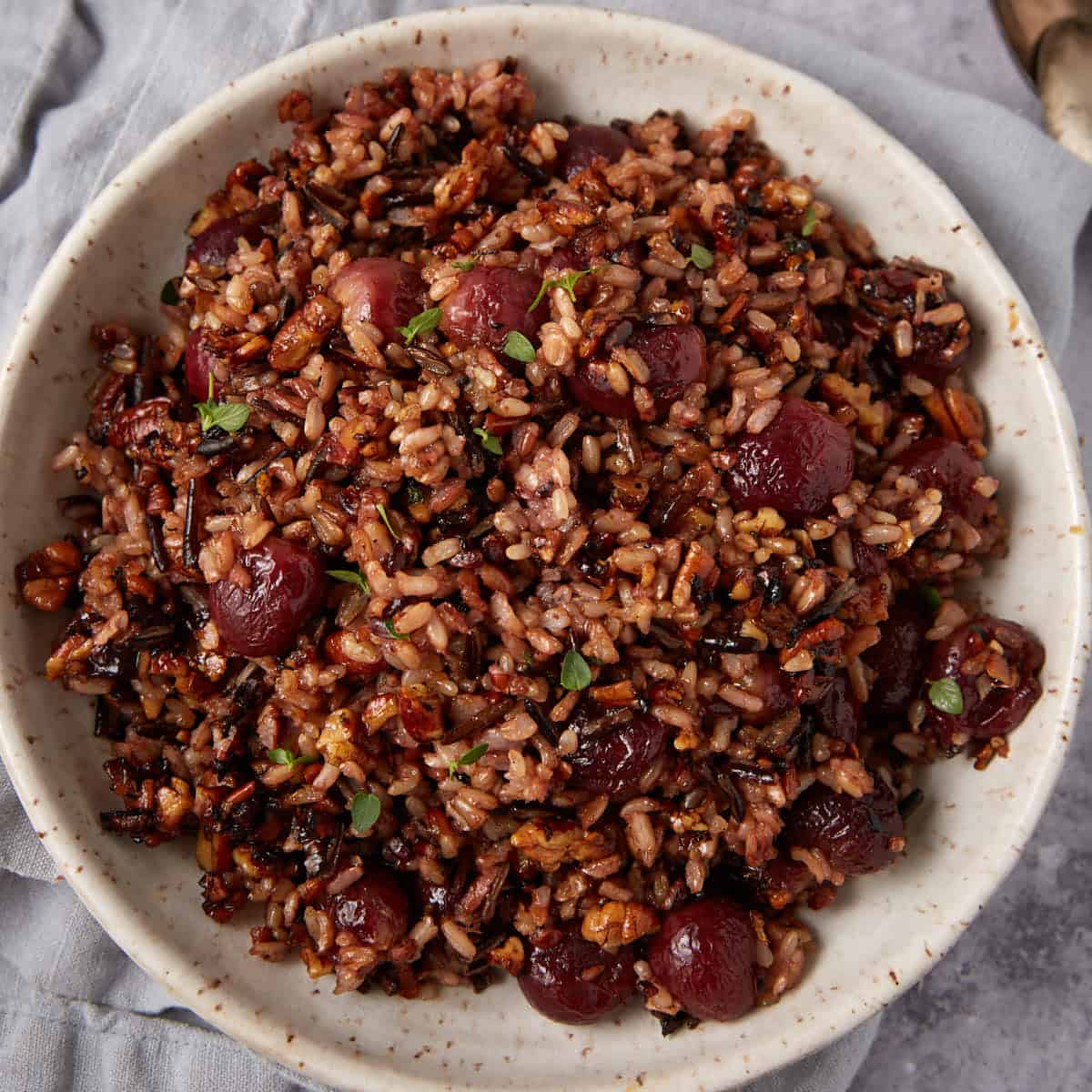wild rice with roasted grapes in a white bowl.