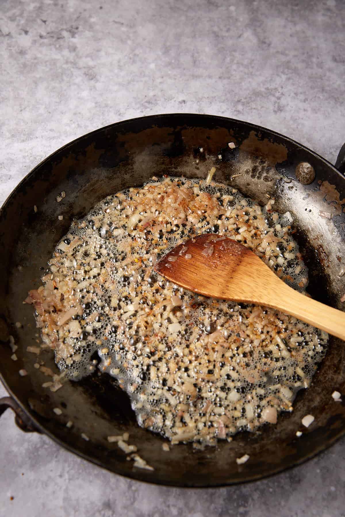 sautéed shallots in a skillet with a wooden spoon.