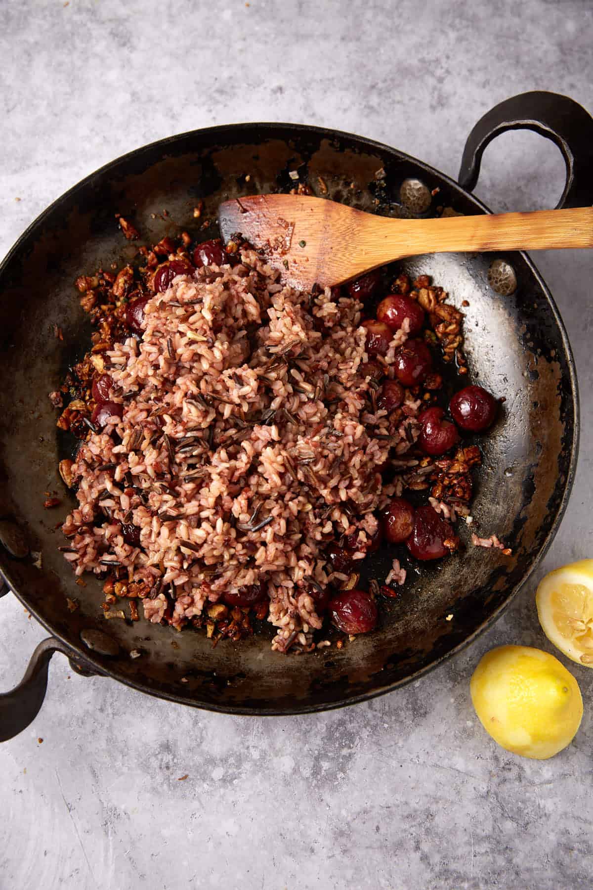 cooked wild rice being added to the roasted grapes, nuts, shallots, and maple syrup.