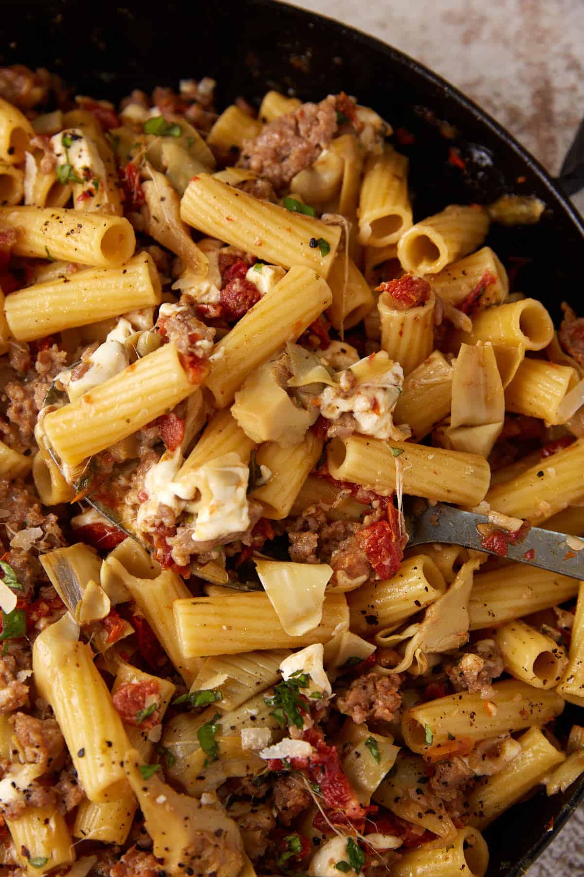 A spoon dipping out a serving of pasta.