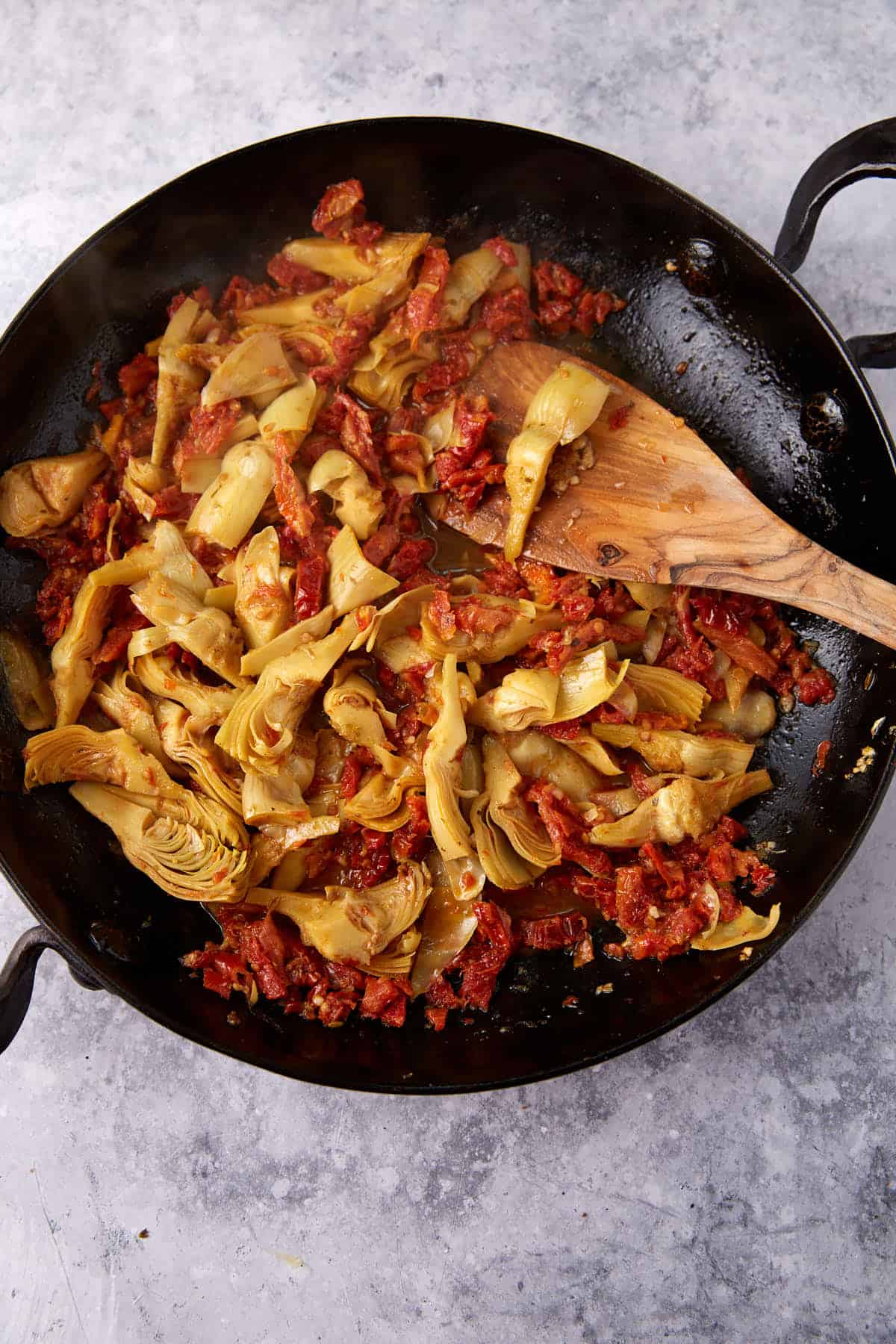 A skillet of artichokes, sun-dried tomatoes and chicken broth.