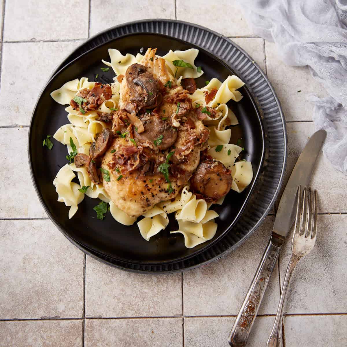 A plate of chicken marsala over egg noodles.