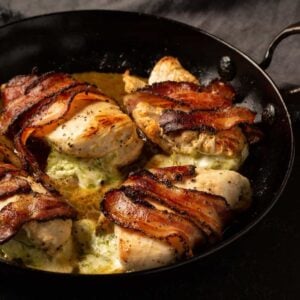 A skillet of bacon wrapped chicken breasts.
