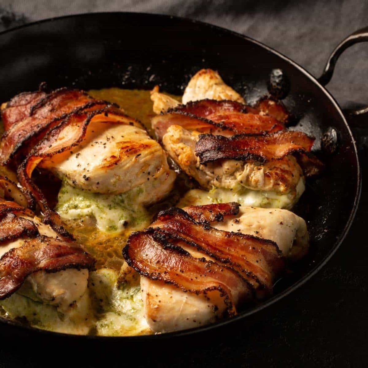 A skillet of bacon wrapped chicken breasts.
