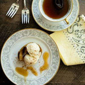 A grilled apple with ice cream next to a cup of coffee.