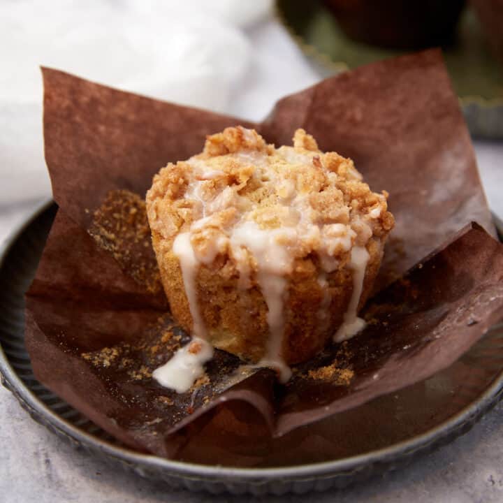 One apple muffin with glaze dripping off.