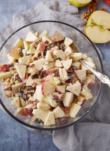 A bowl of apple salad with a serving spoon.