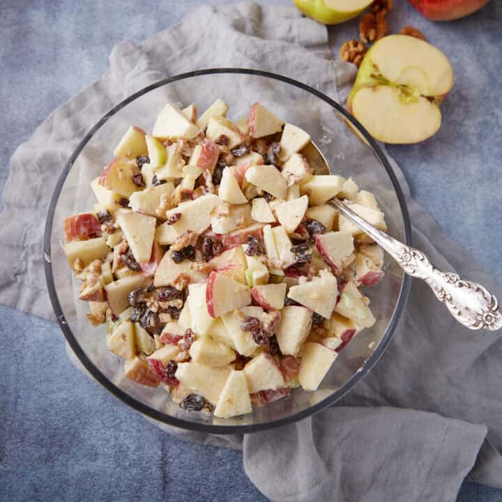 A bowl of apple salad with a serving spoon.
