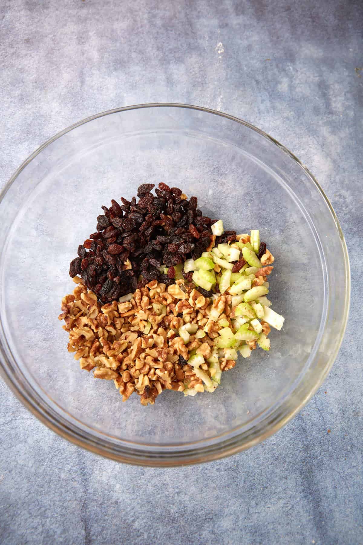 Chopped apples, celery, nuts and raisins in a bowl.