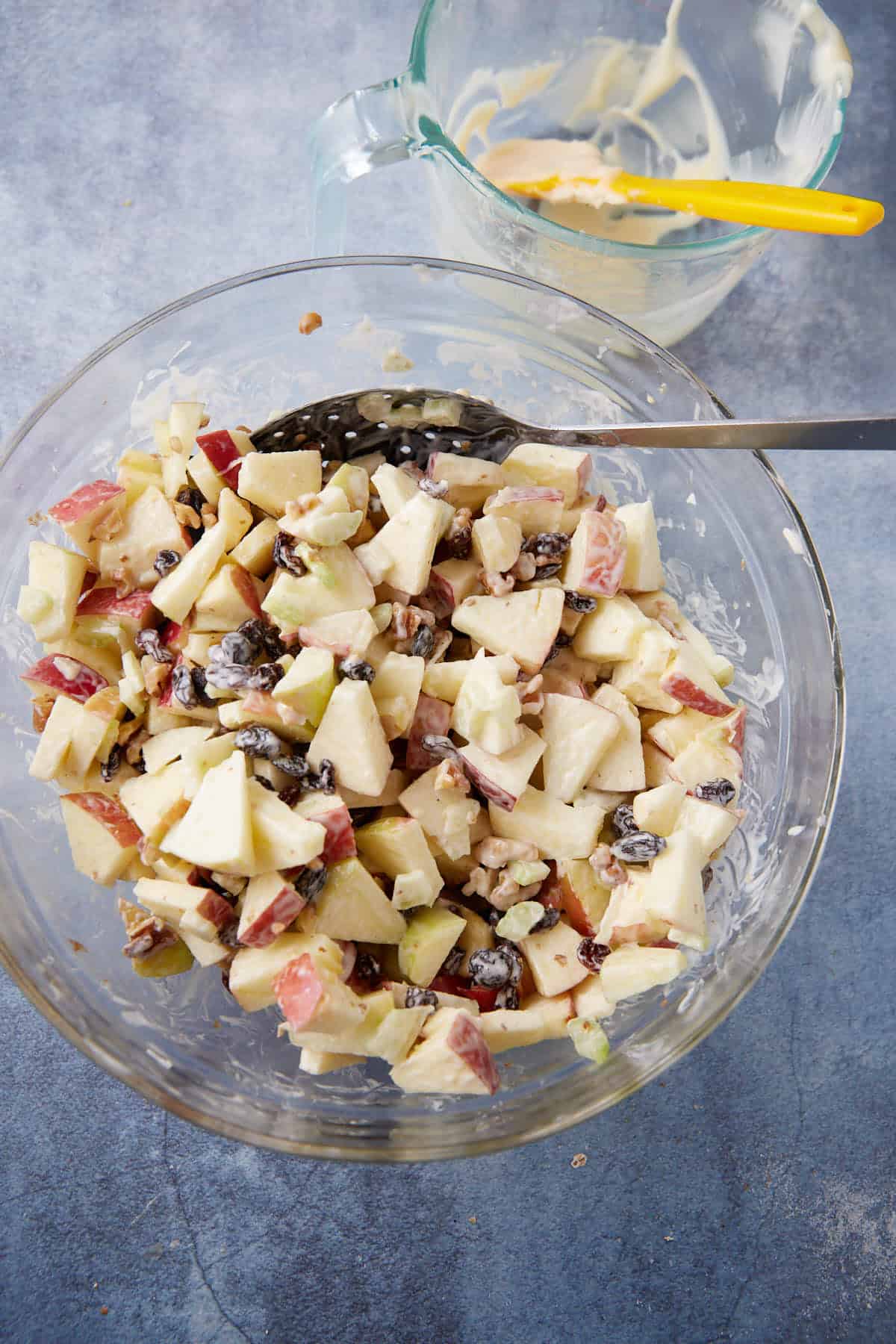 A spoon mixing the dressing into an apple salad.